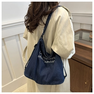Detail of dark blue denim tote bag with Less Mondays More Sundays text on model