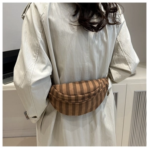 Brown striped fabric belt bag in half-moon shape worn over a stylish beige coat