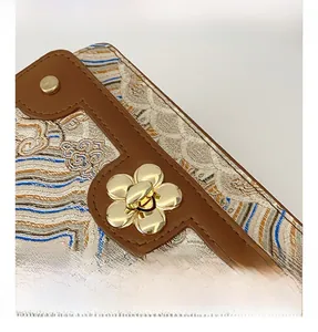 Detail of golden flower buckle on vintage embroidered fabric and brown leather bag