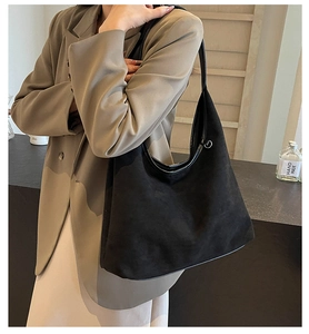 Détail du sac cabas en daim noir souple avec anneau métallique sur la bandoulière