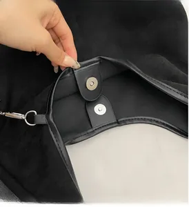 Détail de la boucle magnétique argentée sur un sac bandoulière en suède noir de qualité