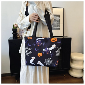 Detailed view of Halloween tote bag with ghost and pumpkin prints held by a model