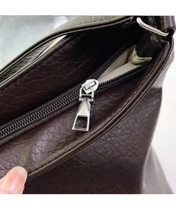 Close-up of polished silver zipper and lychee texture on dark brown leather tote bag