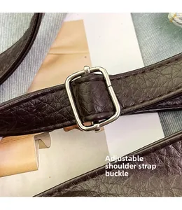 Detail of adjustable dark brown faux leather shoulder strap with silver metal buckle
