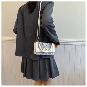 Detail of jacquard small square bag with golden flower lock and woven handle for women