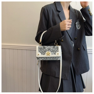 Detail of a retro crossbody bag with traditional wave patterns and golden floral clasp