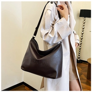 Detail of soft dark brown leather tote bag with embossed fashion text and shoulder strap