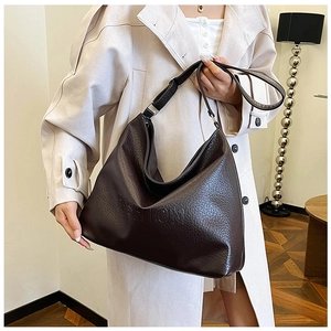 Close-up of embossed FASHION text on a dark brown litchi textured leather hobo bag