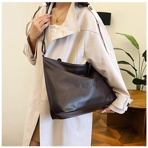 Detail of dark brown leather tote bag with FASHION embossed logo and lychee texture