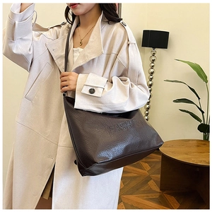 Close-up of the dark brown textured leather tote bag featuring a debossed FASHION logo