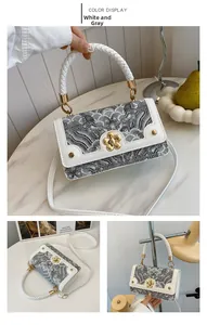 Detail of white and grey shoulder bag with cloud embroidery and gold floral clasp