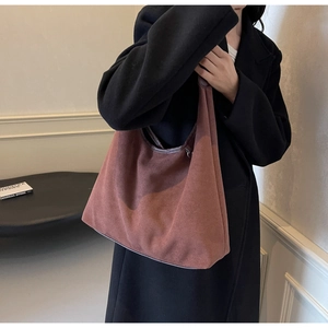Sac hobo rétro en daim marron avec détails en cuir porté sur un manteau en laine noir