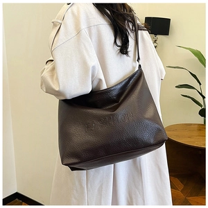 Detail of dark brown leather tote bag with FASHION embossed logo shown on model