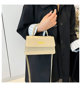 Detail of beige lychee textured handbag with yellow FASHION print and handle