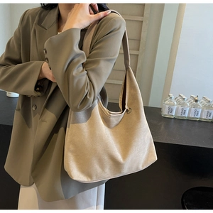 Détail du sac hobo en daim kaki souple porté avec un costume élégant sur un mannequin