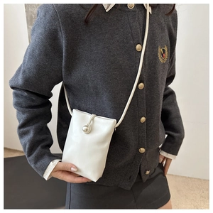 Détail d'un petit sac de téléphone en cuir blanc avec fermeture boule en métal