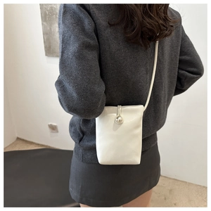 Détail du mini sac bandoulière blanc avec fermoir perle argentée porté par un mannequin