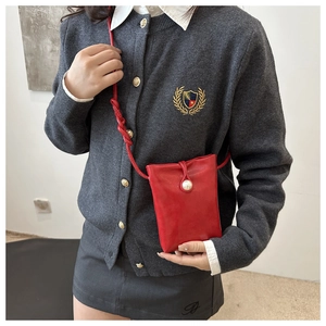 Détail du petit sac à bandoulière rouge avec fermeture perle et bandoulière nouée