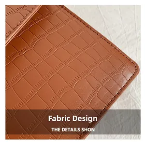 Macro detail of brown crocodile embossed leather with precise stitching on square bag