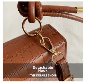 Close-up of brown crocodile texture bag with gold metal ring and detachable strap hook