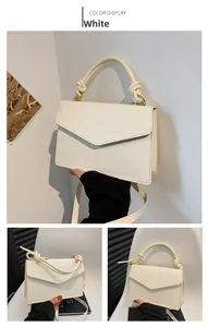 Detail der weißen Handtasche mit Krokodilprägung, Knotengriff und Klappverschluss