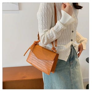 Close-up of caramel crocodile pattern crossbody bag with unique knot shoulder strap detail