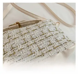 Detailed macro view of the cream tweed fabric and metallic clasp on the crossbody bag