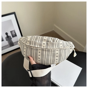 Detailopname van canvas heuptas met zwarte strepen en een brede beige schouderriem