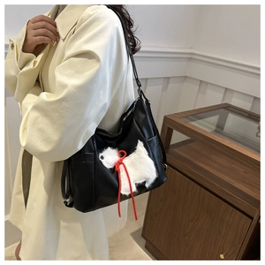 Dettaglio della borsa tote nera in pelle con patch a forma di cane e fiocco rosso