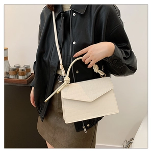 Detailed view of white crocodile pattern crossbody bag with knotted handle detail
