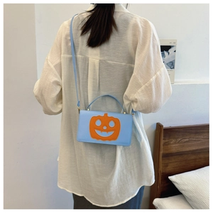 Detail of light blue PU leather pumpkin crossbody bag with orange face patch on a model