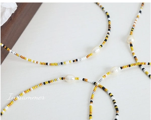 Detail of beaded necklace featuring natural freshwater pearls and colorful glass seed beads