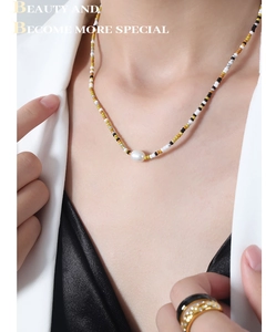 Close-up of glass beads and pearl pendant necklace worn by a fashion model