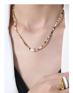 Detail of beaded necklace with freshwater pearl and rings on woman in white suit