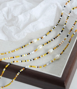 Detail of handmade beaded necklace with natural freshwater pearls and vibrant seed beads