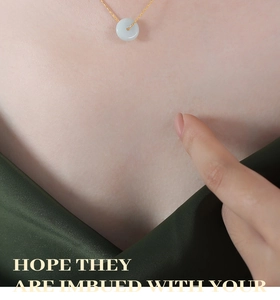 Détail du pendentif donut en jade sur chaîne dorée porté sur un tissu en soie