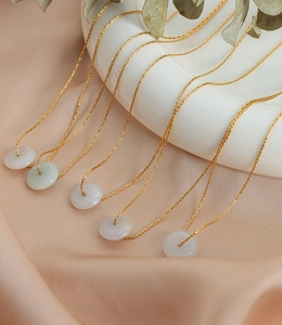 Détail de chaînes plaquées or 18k avec cinq pendentifs en jade sur soie rose