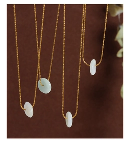 Vue détaillée de plusieurs pendentifs en jade Hetian sur d'élégantes chaînes dorées