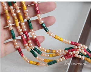 Detail of beaded necklace with irregular pink pearls and vibrant cylindrical natural stones
