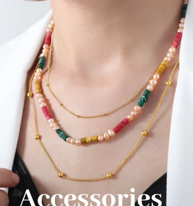 Close-up of layered necklace with pink pearls and colorful beads on white suit
