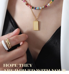Detail of layered gold titanium necklaces with colorful beads and a square pendant