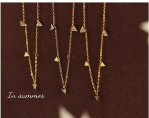 Détails de colliers dorés avec pendentifs triangulaires et incrustations de zircons