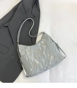 Close-up of silver-gray metallic hobo bag with five gold butterfly accents on wrinkled fabric