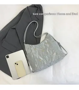 Detailed view of silver pleated tote bag with gold butterfly buckle next to an iPad