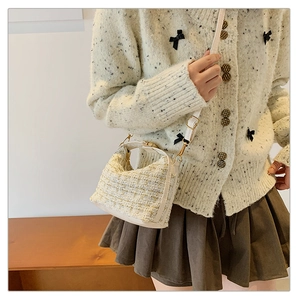 Close-up of beige tweed shoulder bag with woven texture and gold thread accents