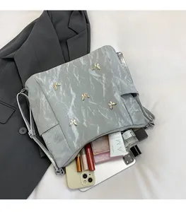 Detail view of large capacity silver bag with gold butterfly accents and daily items