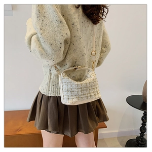 Close-up of wool tweed crossbody bag with golden hardware and cream leather details