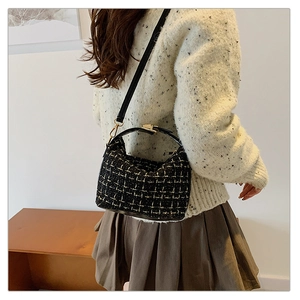 Close-up of black tweed shoulder bag with golden metallic clasp for autumn and winter