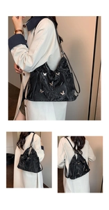 Macro detail of black crinkled leather tote bag with silver butterfly metal accents