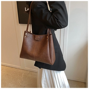 Detail of vintage brown PU leather tote bag with gold rivets and fashion embossed strap